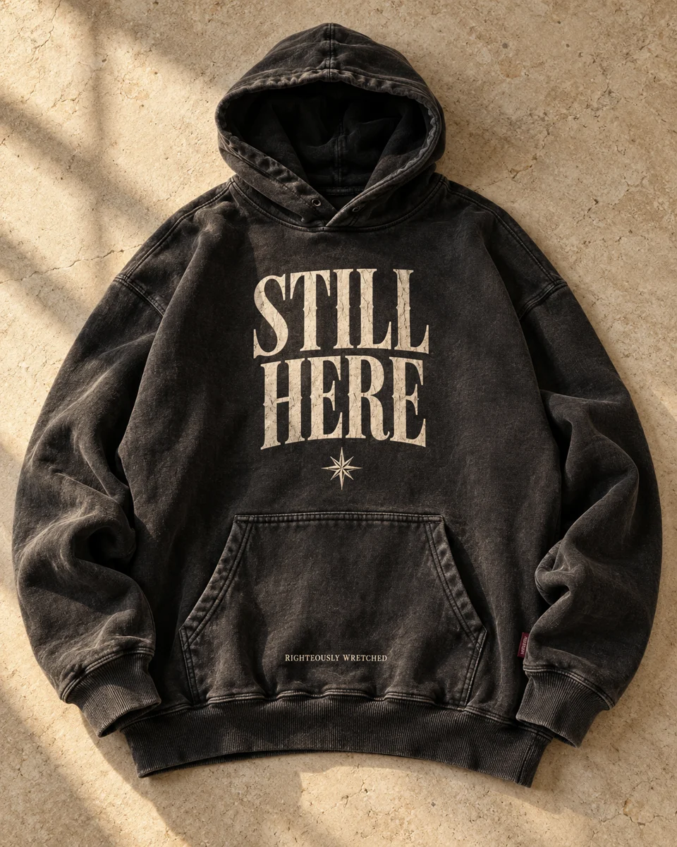 Design concept: washed-black Still Here hoodie with ivory lettering and a stitched star.